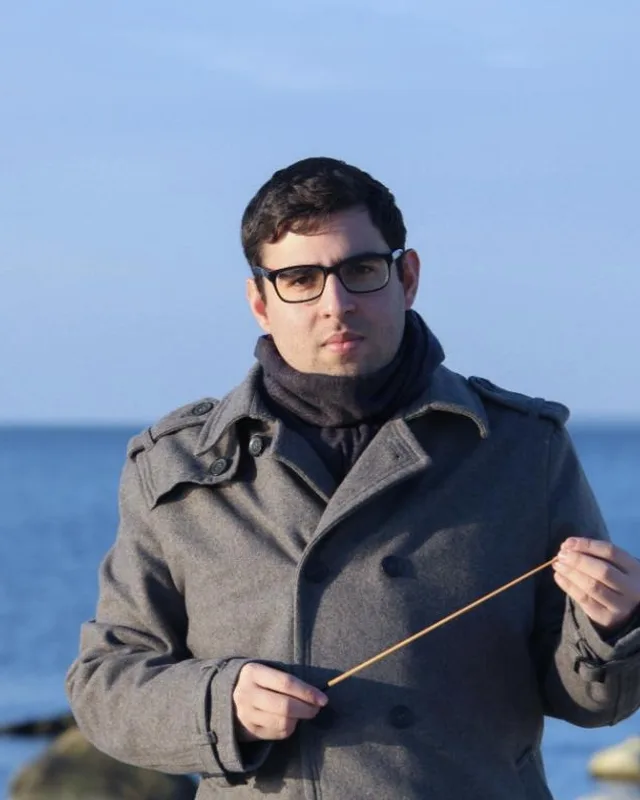 Eladio Aguilar holding a conductor’s baton by the sea