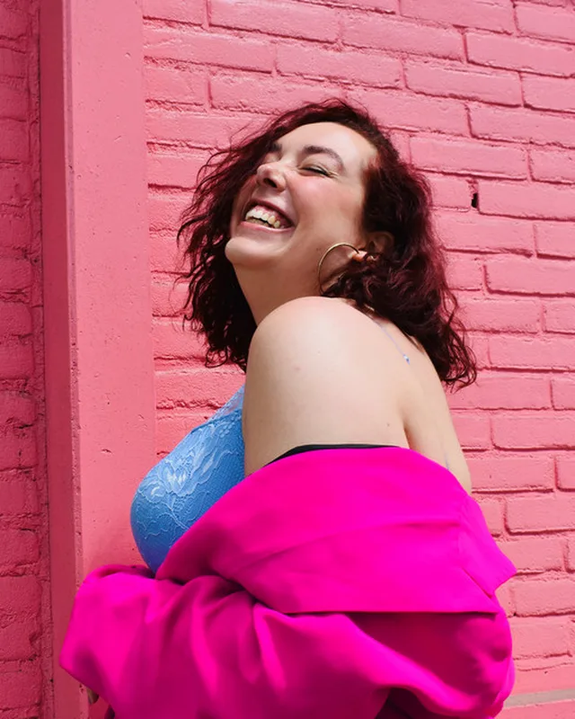 Sébastienne laughing against a pink brick wall